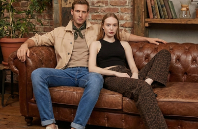 Kahverengi kanepe üzerinde judjeans pantolunu giyen iki kişi.